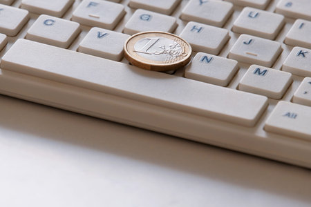 The concept of online sales. E-business. Coin in one Euro on the computer keyboard close-up....