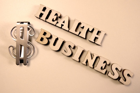 Health business. The concept of corruption in medicine. The inscription of wooden letters and a metal dollar sign. Illness and money.の写真素材