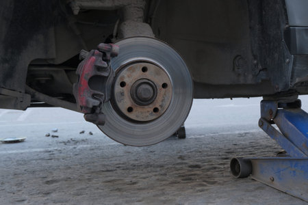 An old dirty car without a wheel is jacked up. Tire fitting. Close-up wheel arch. Repair of tires or...