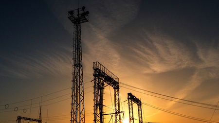 High-voltage electrical substation with wires, poles and observation towers. Copy space. Silhouette at sunset in the evening sky.の写真素材
