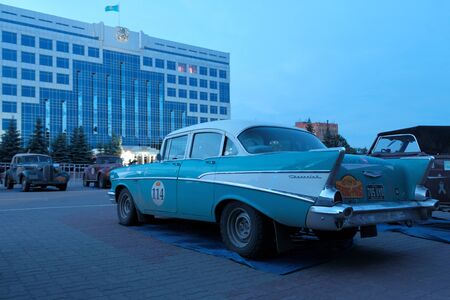 Kazakhstan, Kostanay, 2019-06-20, A retro Chevrolet car is parked in the town square opposite the government building. Back view. The 7th Peking to Paris Rally Motor Challenge. Evening blue light.のeditorial素材