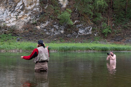 Fly fishing and undressed photographer in the river. Photosession in nature. Reportage. Mountain...