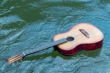 Acoustic guitar floats in the water. The concept of flood, shipwreck, tragedy of musicians in...