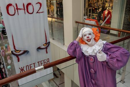 19-08-16, Kostanay, Kazakhstan. A guy in an IT suit stands next to a poster for a new film. Cosplay for carnival or for halloween. A very scary clown with teeth leaned on the railing.のeditorial素材