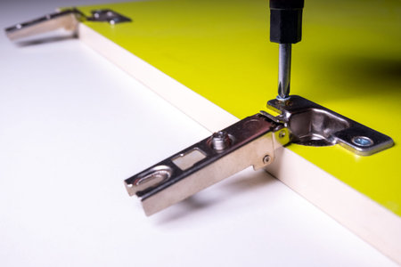 Installation of furniture canopy for doors on a green door made of chipboard. Screw tightening with...