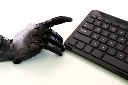 The prosthesis of a human hand raised his index finger to press a key. Black robot hands and...