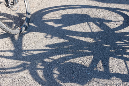 Shadow and wheel of a bicycle on the pavement. Abstract background. The concept and promotion of a...