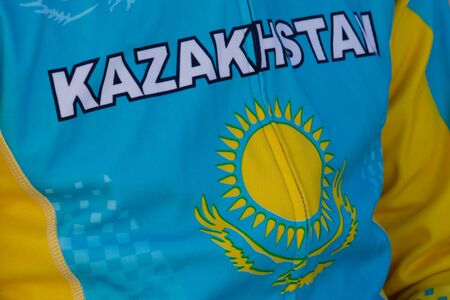 The inscription, the eagle and the sun on the chest. State symbols of the republic. Cycling and bike ride. Sportswear of Kazakhstan athlete. Sport's event.の写真素材