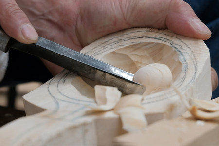 Wood carving. A sharp cutter removes chips in a wooden block. Traditional manufacture of a spoon in...