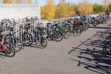Kostanay, Kazakhstan, 2019-10-06. Parking bicycles of different brands in nature. Bike ride. Autumn, yellow leaves on the trees. Long shadows on the pavement. Copy space.のeditorial素材