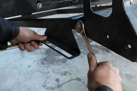 Close-up of male hands tightening a nut on a metal product. Technician in factory at machine maintenance working with wrenchの写真素材
