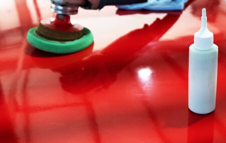 Tools and means for polishing. Glossy red surface. Noise, film grain. Copy space. White bottle with polish in the foreground.の写真素材