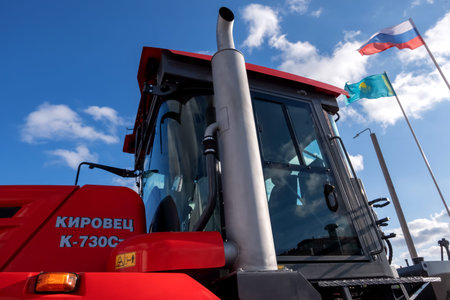 Kostanay, Kazakhstan, 2019-10-23, Cabin of a red tractor of the Kirovets K-730 and flags against the...
