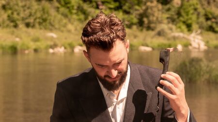 A businessman in a suit during vacation holds in his hand a handset that is on fire. The concept of hated work, humor about the technical support hotline or non-observance of safety measures. Toning.の写真素材