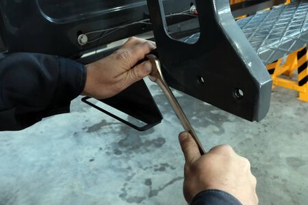 Male hands with a wrench. Close-up. A technician at a machine service plant tightens a bolt or nut.の写真素材