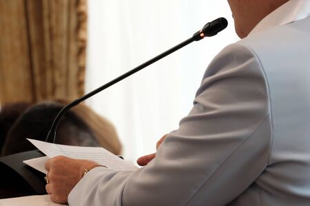 Oratory of an abstract woman in front of a microphone. Report meeting, discussion, government speech, speaker, business girl or official. Recording speech on a microphone.の写真素材