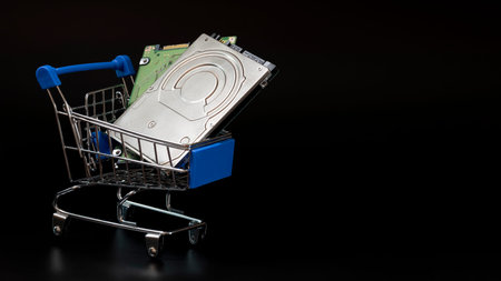 Two laptop hard drives in a blue shopping basket. Black background. Sale and discount concept, black...