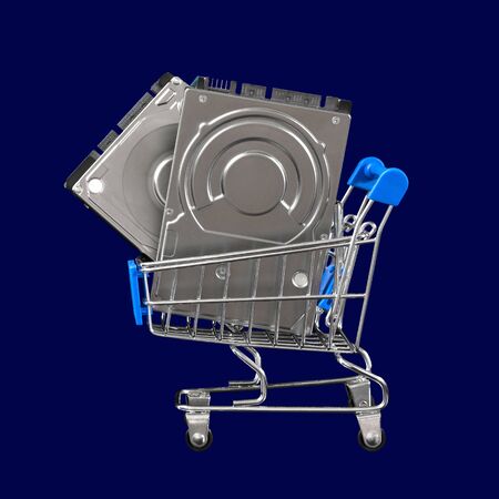 Two computer hard drives for the price of one in a shopping cart. Promotion and sale of peripherals and accessories for PC and laptop. Concept for cyber monday advertisement. Close-up. Isolated on a blue background.の写真素材