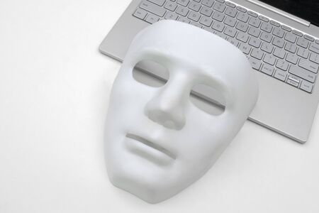 White mask and laptop closeup. The criminal concept of cyber attack or danger from hackers.の写真素材