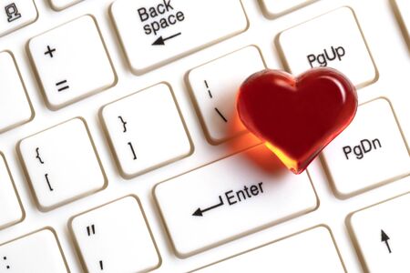 Red heart on a white computer keyboard. Close-up. The concept of gifts for Valentine's Day, love correspondence and meeting on social networks. Request to like and repost, click on enter.の写真素材