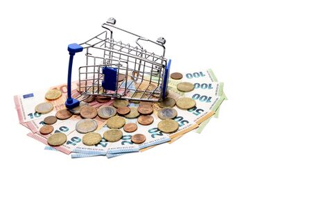 The stroller for shopping is tipped over on a fan of Euro banknotes and coins. The concept of a consumer basket and spending money in Europe, crisis, discounts, interest return. Banknotes in the amount of 500 euros. Template for black friday, cyber monday.の写真素材