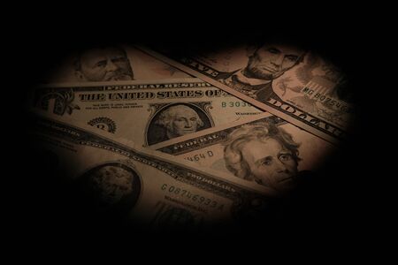 Heart shaped light spot on the background of dollar bills. The concept of discounts for Valentine's Day, wedding and love sales. Black vignetting.の写真素材