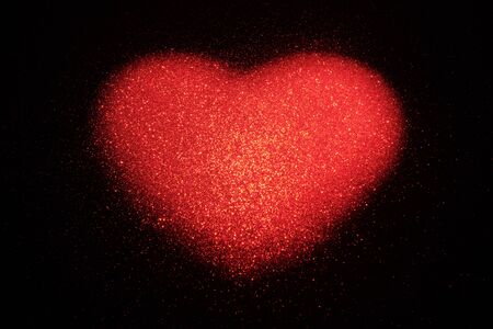 Abstract red heart made of shiny dots on a black background. The concept of congratulations on Valentine's Day, love blank, meeting and flirting with a place for copy space.の写真素材