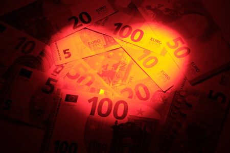 Heart shaped light spot on a background of euro banknotes. The concept of discounts for Valentine's Day, wedding and love sales. Dark vignetting. Copy spaceの写真素材