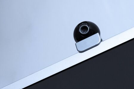 A web camera for video recording and video surveillance is installed on the monitor. Equipment for computer . The concept of cybersecurity, remote monitoring, protection or viewing privacy, big brother. Copy space. Close-up.の写真素材