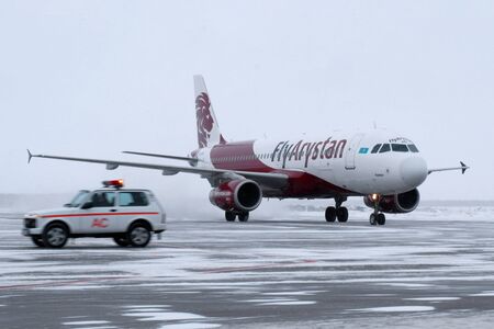 2019-12-18 Kostanay, Kazakhstan. Landing of the Airbus A320 aircraft at the winter airfield. Escort of the aircraft by car Niva. The first flight of FlyArystan air company from Nur-Sultan to Qostanay.のeditorial素材