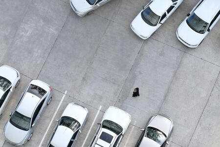 A man is walking in a car park. Driver, passerby or buyer of cars. Copy space. View from above.の写真素材