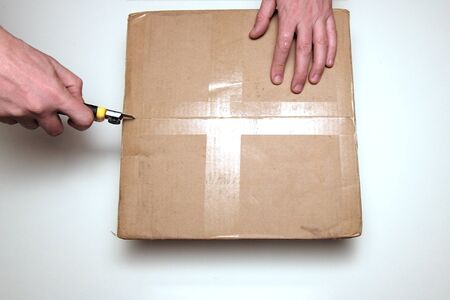 Men unpacking boxknife knife. View from above. The concept of delivery and verification of online purchases or opening a gift.の写真素材