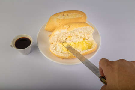 Brazilian Wheat Baked French Bread and coffee, on white background and buttering bread - perspective view.の写真素材