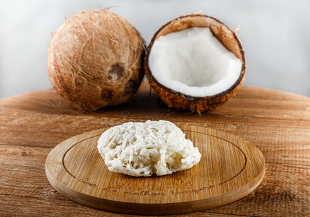 Cocada, coconut candy. White cocada on wooden table with two coconuts behind and white background,...
