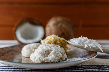 White and yellow cocada on wooden table with wooden spoon with grated coconut - perspective view,...