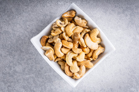 Cashew nuts in crockery pot on white wooden background. Top view.の写真素材