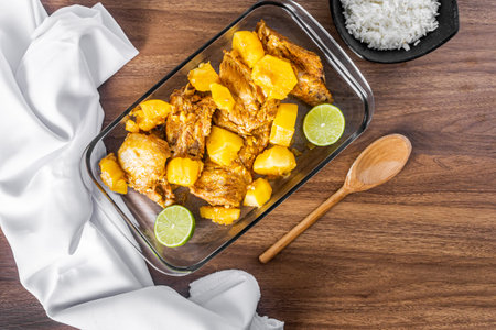 Pork ribs cooked in a pressure cooker on a wooden table. White towel around the bowl. Rice and a wooden spoon. Top view.の写真素材