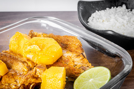 Pork ribs cooked in a pressure cooker on a wooden table. White towel around the bowl. Rice and a wooden spoon. Close view.の写真素材