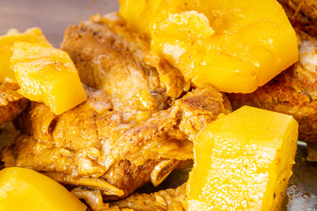 Pork ribs cooked in a pressure cooker on a wooden table. White towel around the bowl. Rice and a wooden spoon. Close view.の写真素材