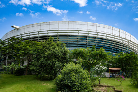 Round building with beautiful green vegetation in the foreground and blue sky with few clouds.の写真素材
