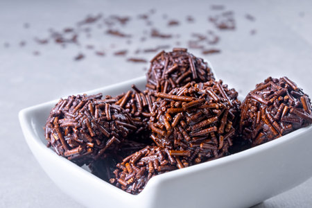 Several brigadeiro sweets on a white bowl with chocolate sprinkles lying on the table. Typical...