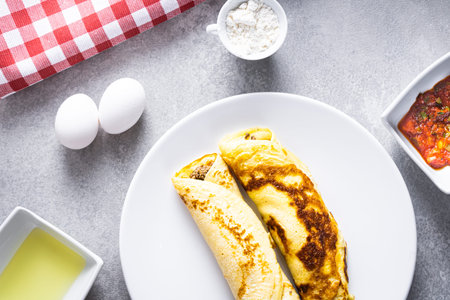Delicious meat pancakes on a white plate, with eggs, wheat, olive oil, tomato sauce and checkered...