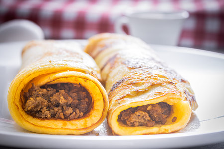 Delicious meat pancakes on a white plate, with eggs, wheat, olive oil, tomato sauce and checkered...