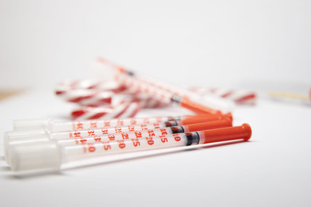insulin syringes and candy caramel canes on a white table