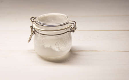 glass jar with coconut oil on a white wooden tableの写真素材