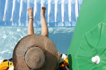 Girl at the pool with a hatの写真素材