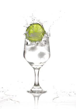 A slice of lemon falls in a glass of water and ice.の写真素材
