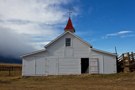 White barn with a red roof as a storm cloud is coming in