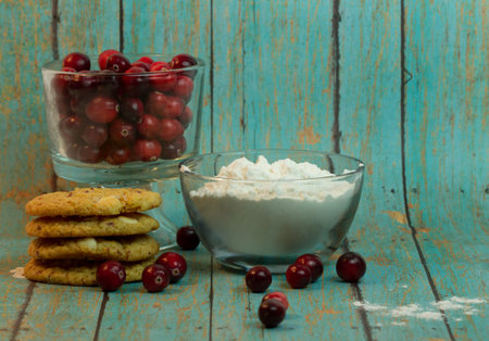 Stacked Cranberry Chocolate Chip Cookies with a bowl whole Cranberries and flour on a wooden plank backgroundの写真素材