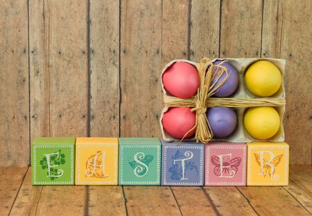 Multi color Easter blocks with twine bow easter eggs on a wood plank backgroundの写真素材